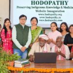 Traditional Adivasi elder operating a laptop during the inauguration of Hodopathy.org, Hodopathy.in and Hodopathy.com in Giridih, Jharkhand, on 8 October 2026, with Rajeev Singh and community members.